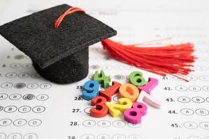 número de matemáticas colorido con sombrero de graduación y lápiz en el fondo de la hoja de respuestas, estudio de educación concepto de enseñanza de aprendizaje de matemáticas. foto