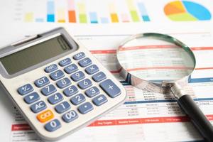 Magnifying glass and calculator on charts graphs paper. Financial development, Banking Account, Statistics, Investment Analytic research data economy, Stock exchange trading, Business office concept. photo