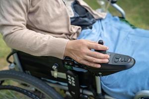 mujer asiática paciente en silla de ruedas eléctrica con joystick y control remoto en la sala del hospital de enfermería, concepto médico fuerte y saludable foto