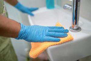 mucama limpieza lavado y fregado lavabo en inodoro en casa. foto