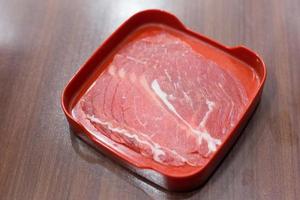 Sliced pork was served in Shabu, Sukiyaki or grill restaurant and dip with sauce on the wooden table. photo