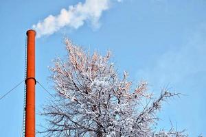 tubería en una planta de energía térmica humo contra el cielo azul. foto