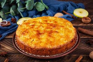 Delicious homemade apple pie on wooden background. Apple pie with ingredients, apples and cinnamon photo