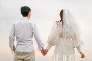 Happy young Asian couple in bride and groom clothing photo