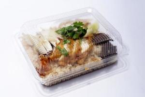 Side view of plastic box for food of Hainanese chicken glutinous rice mix with Fried Chicken. On white floor or isolated white background. photo