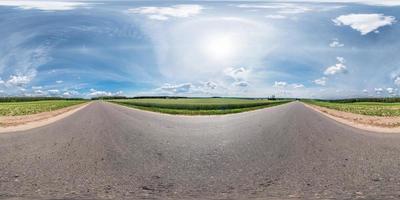 panorama esférico completo y transparente de 360 por 180 grados de ángulo de visión en la carretera asfaltada entre campos en un día soleado de verano con halo en proyección equirectangular, skybox vr contenido de realidad virtual foto