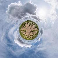 tiny planet in blue sky with sun and beautiful clouds. Transformation of spherical panorama 360 degrees. Spherical abstract aerial view. Curvature of space. photo