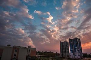 por la noche nubes onduladas y rizadas de una impresionante puesta de sol contra el fondo de edificios de apartamentos de varios pisos foto