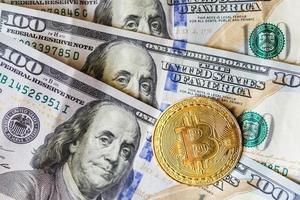 virtual money golden bitcoin on hundred dollars bills background. Exchange bitcoin cash for a dollar. photo