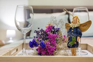 decoración de bodegones a partir de dos copas de vino vacías, un juguete de ángel de trapo hecho en casa y un ramo de flores secas. foto
