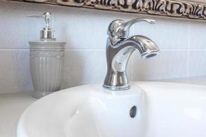 Soap and shampoo dispensers on Water tap sink with faucet in expensive loft bathroom photo