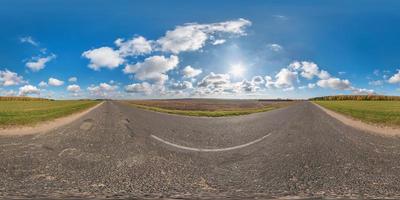 Full spherical seamless panorama 360 degrees angle view on no traffic asphalt road among fields in sunny day with awesome clouds. 360 panorama in equirectangular equidistant projection, VR AR content photo