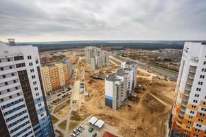 vista panorámica sobre la construcción de la nueva torre del barrio edificio alto de varios pisos sin terminar desde una vista de pájaro con bosque en el fondo foto