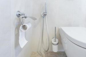 toilet and detail of a corner shower bidet with toilet paper holder on wall mount shower attachment photo