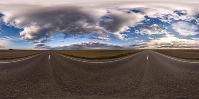 vista de ángulo de 360 grados de panorama hdri esférico completo sin tráfico en carretera asfaltada entre campos por la noche antes de la puesta del sol con cielo nublado. Panorama 360 en proyección equirrectangular, contenido vr ar foto