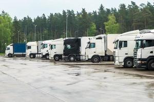 camiones en fila con contenedores en el estacionamiento cerca del concepto forestal, logístico y de transporte foto