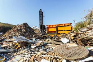 Excavator sorts plastic garbage at waste processing plant. Separate garbage collection. Recycling and storage of waste for further disposal. Business for sorting and processing of waste. photo