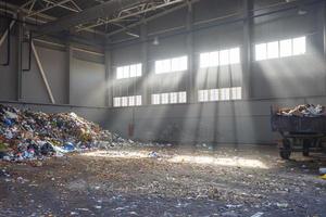 trash sorting and recycling workshop with trailer at the waste processing plant with sun rays. Separate garbage collection. Recycling and storage of waste for further disposal. photo