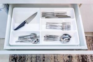 cutlery spoons forks knives and tea spoon on the shelf in the kitchen cupboard photo