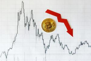 Depreciation of virtual money bitcoin. Red arrow and golden Bitcoin on paper forex chart index rating go down on exchange market background. Concept of depreciation of cryptocurrency. photo