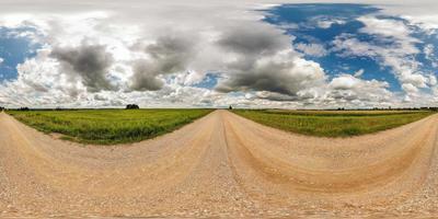 panorama esférico completo y transparente de 360 por 180 grados de ángulo de visión en camino de grava entre campos en un día soleado de verano con impresionantes nubes en proyección equirectangular, skybox vr contenido de realidad virtual foto