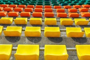 filas multicolores de asientos de plástico en el estadio foto