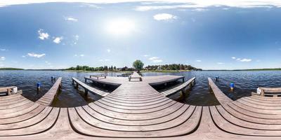 panorama completo sin costuras 360 por 180 vista angular muelle de madera para barcos en un enorme lago forestal en un día soleado de verano en proyección equirectangular, contenido skybox vr. viento de libertad foto