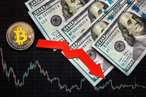 Depreciation of virtual money bitcoin. Red arrow, silver bitcoin and dollars on black paper forex chart index rating go down on exchange market background. Concept of depreciation of cryptocurrency. photo