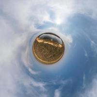 pequeño planeta en el cielo azul con sol y hermosas nubes. transformación de panorama esférico 360 grados. vista aérea abstracta esférica. curvatura del espacio. foto