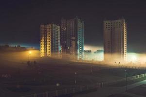 night panorama of residential area with high-rise buildings in the fog early in the morning photo