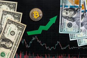 profitable investment of virtual money bitcoin. Green arrow and silver Bitcoin on black paper forex chart index rating go up on exchange market background. Concept of appreciation  of cryptocurrency. photo