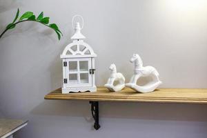 interior decoration toys. White decorative wooden latern lights and ceramic horses in expensive interior photo