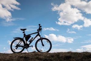 Bike silhouette in blue sky with clouds. symbol of independence and freedom photo