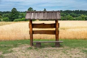 a wooden gazebo bench in a wheat field photo