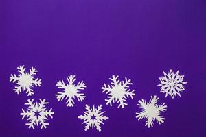 White paper snowflakes different shapes and sizes on violet background. Top view. photo