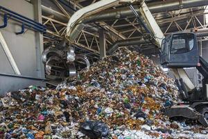 excavadora en la clasificación primaria de basura en la planta de procesamiento de residuos. recolección de basura por separado. reciclaje y almacenamiento de residuos para su posterior eliminación. negocio de clasificación y tratamiento de residuos. foto