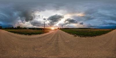 panorama esférico completo sin fisuras vista en ángulo de 360 grados en camino de grava entre campos al atardecer con impresionantes nubes antes de la tormenta en proyección equirectangular, vr ar contenido de realidad virtual foto