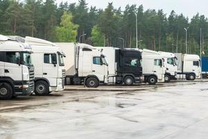 Trucks in a row with containers in the parking lot near forest , Logistic and Transport concept photo