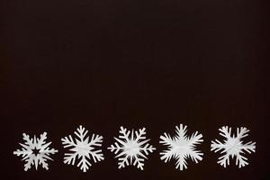 White paper snowflakes different shapes and sizes on brown cardboard background. Top view. photo