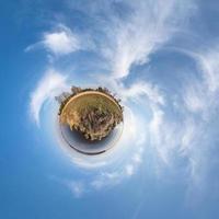 Little planet transformation of spherical panorama 360 degrees. Spherical abstract aerial view in field with awesome beautiful clouds. Curvature of space. photo