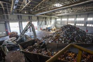 Excavator on primary sorting of garbage at waste processing plant. Separate garbage collection. Recycling and storage of waste for further disposal. Business for sorting and processing of waste. photo