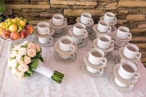 View of the served for decorated table with tea set cups fruits and wedding bouquet photo