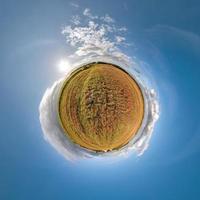 yellow tiny planet in blue sky with beautiful clouds. Transformation of spherical panorama 360 degrees. Spherical abstract aerial view. Curvature of space. photo