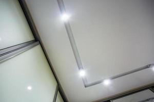 halogen spots lamps on suspended ceiling and drywall construction in in empty room in apartment or house. Stretch ceiling white and complex shape. photo