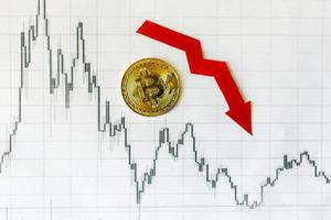 Depreciation of virtual money bitcoin. Red arrow and golden Bitcoin on paper forex chart index rating go down on exchange market background. Concept of depreciation of cryptocurrency. photo