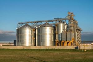 silos de plata en la planta de fabricación agrícola para el procesamiento, secado, limpieza y almacenamiento de productos agrícolas, harina, cereales y granos foto