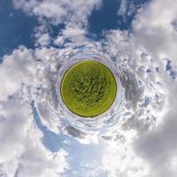 Little planet transformation of spherical panorama 360 degrees. Spherical abstract aerial view in field with awesome beautiful clouds. Curvature of space. photo