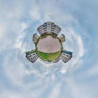 tiny planet in blue sky with clouds in modern multi-storey multi-apartment residential complex of urban development. Transformation of spherical 360 panorama in abstract aerial view. photo