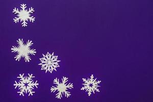 White paper snowflakes different shapes and sizes on violet background. Top view. photo