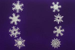 White paper snowflakes different shapes and sizes on violet background. Top view. photo